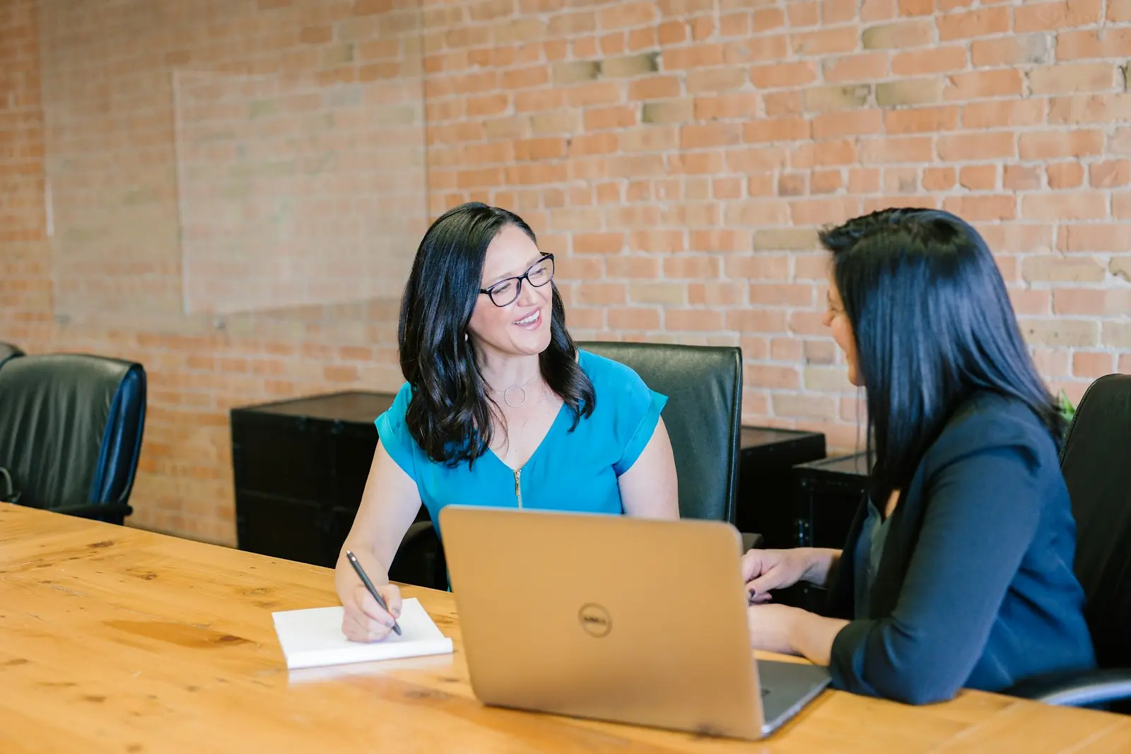 Two colleagues talking across a meeting table