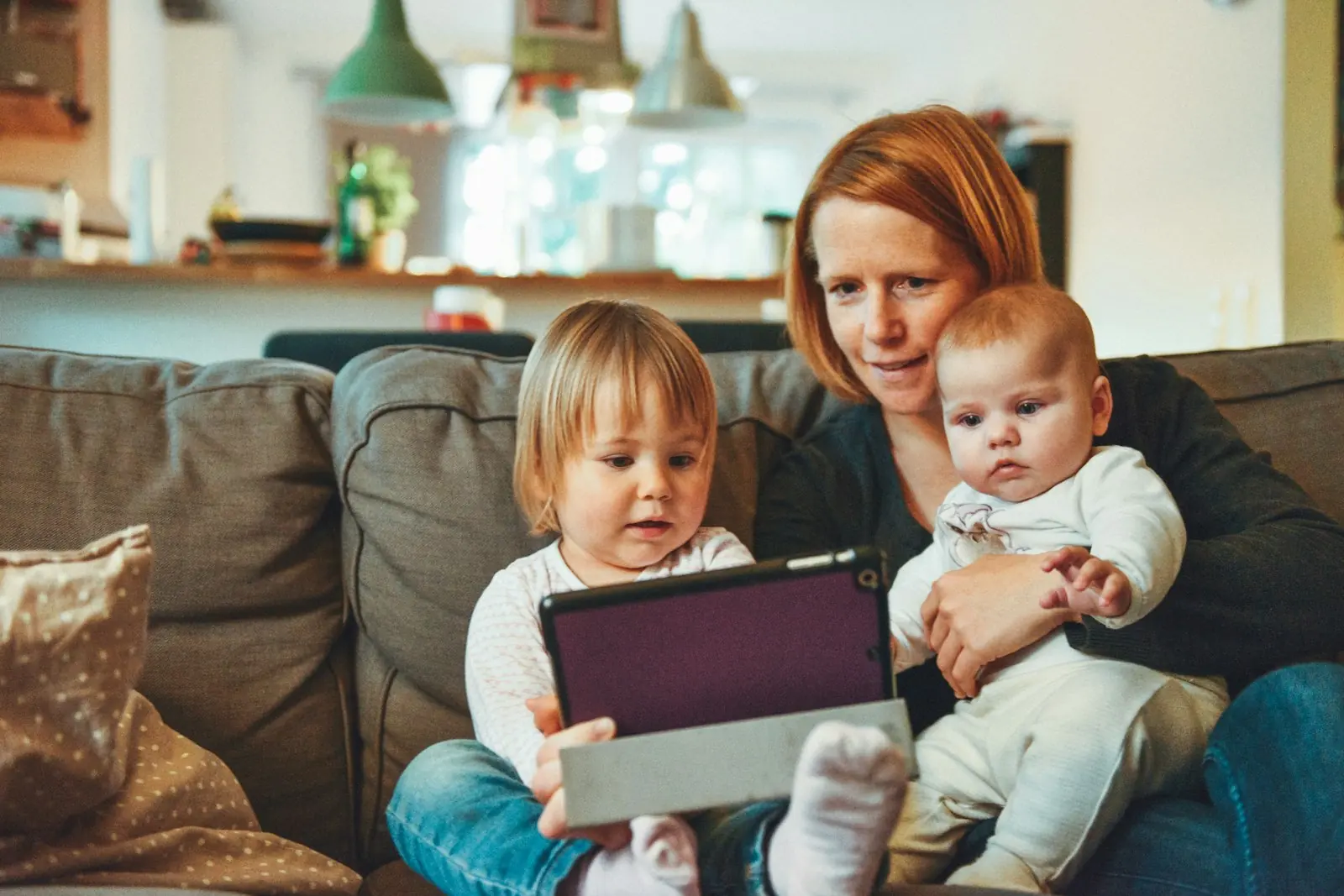 A parent and two children together on a sofa at home