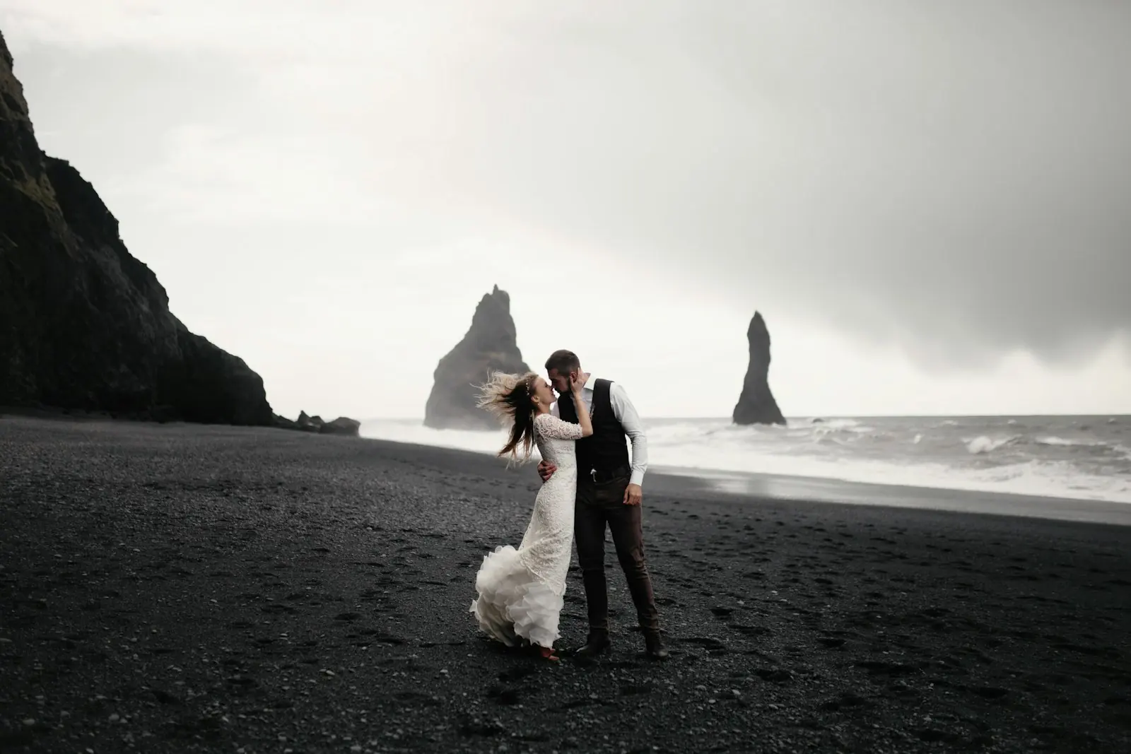 A couple in wedding clothes standing together on a dark beach