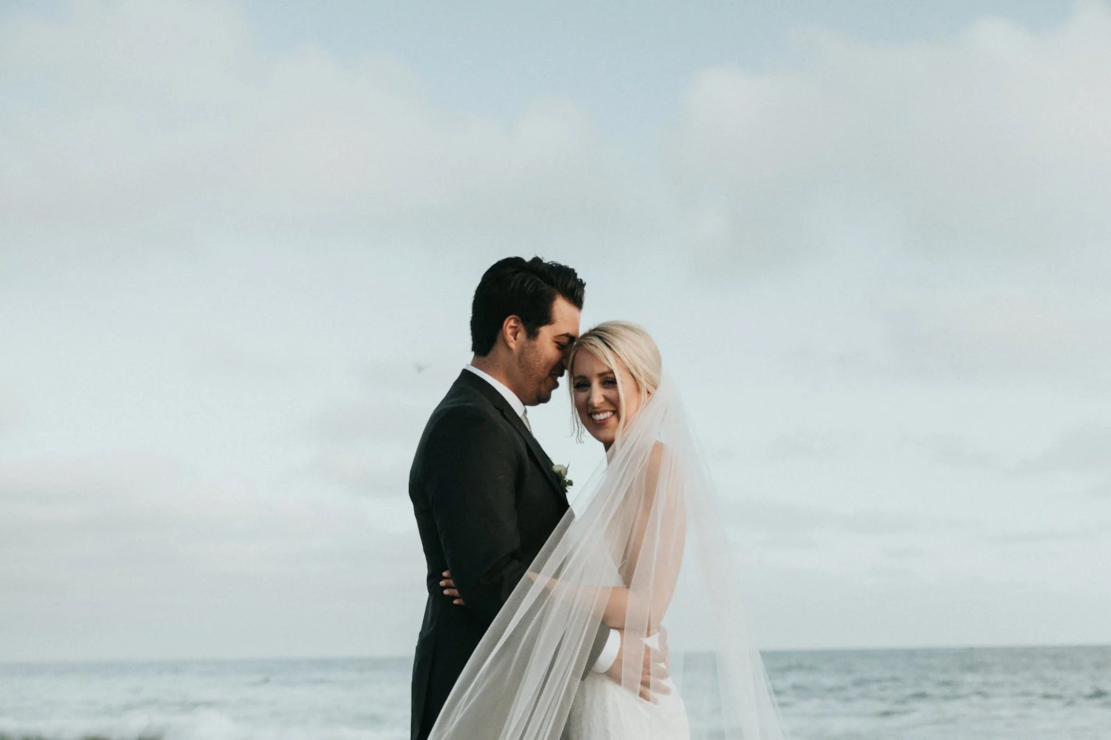 A couple in wedding clothes standing together in soft daylight
